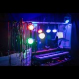 RGB accent lights on the overhead bar at Studio San Francisco, with monitoring headphones and cables hanging above a synth and laptop