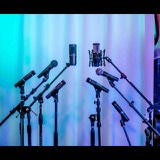 Part of the Studio San Francisco microphone locker: dynamic and condenser mics on stands in front of the lit curtain wall