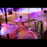 Close-up of cymbals and snare on the studio's drum kit under coloured stage lighting