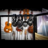Four pairs of Tascam and Audio-Technica monitoring headphones on the studio's cue rail, with guitars behind
